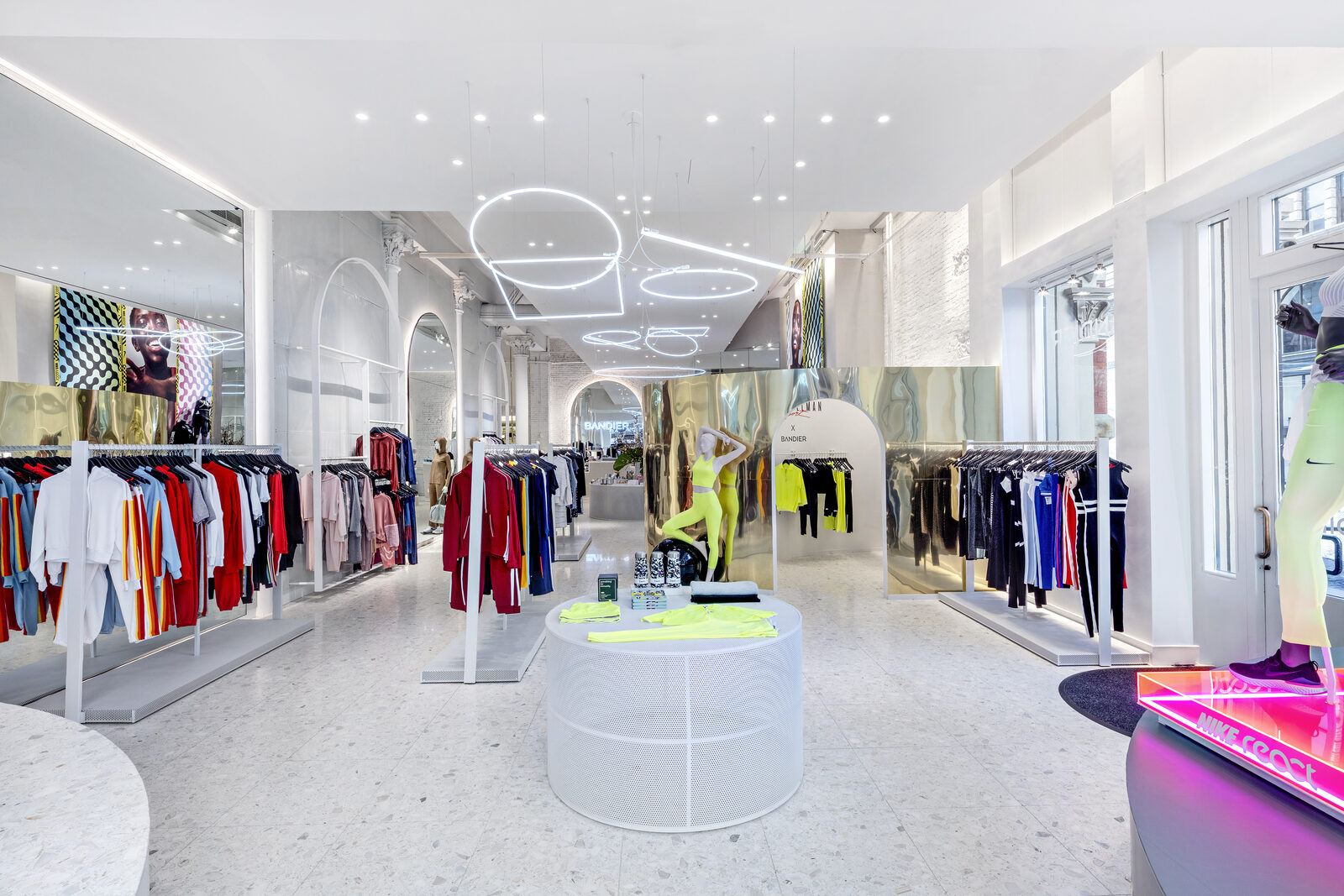 Bandier on Bond store interior with bright clothing racks, sculptural ceiling lights, gold display panels, and Nike merchandise.
